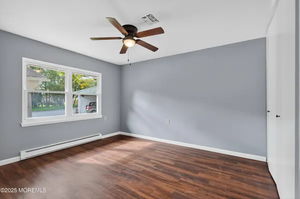 an empty room with wooden floor fan and windows