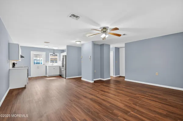 a view of an empty room with a window and wooden floor