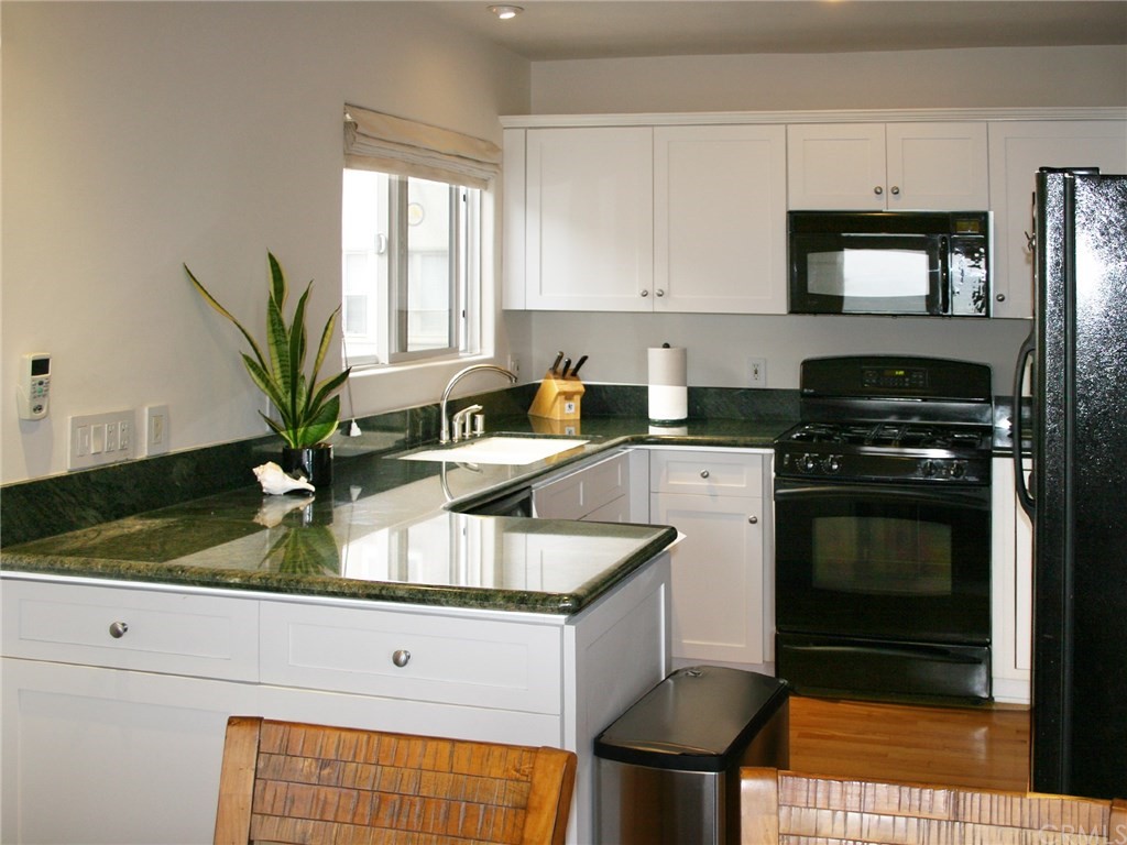 614 The Strand Manhattan Beach, CA 90266 - Photo 36 of 41 a kitchen with granite countertop a stove a sink and a white cabinets