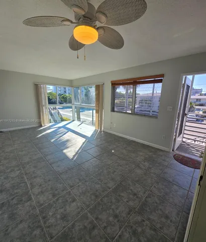 a view of an empty room with window and chandelier fan