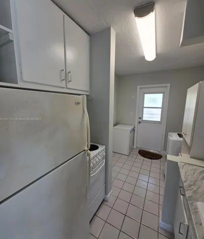 a kitchen with white cabinets appliances and a window