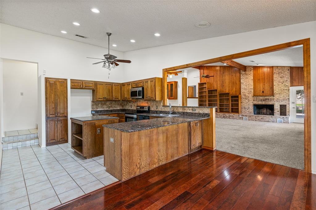 7508 Ravenswood Road Granbury, TX 76049 - Photo 16 of 40 a kitchen with stainless steel appliances granite countertop a stove and a refrigerator