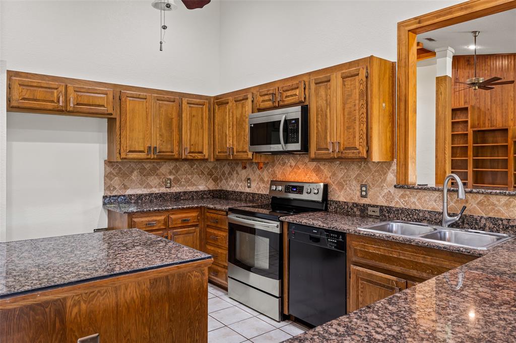 7508 Ravenswood Road Granbury, TX 76049 - Photo 17 of 40 a kitchen with stainless steel appliances granite countertop a sink stove and microwave