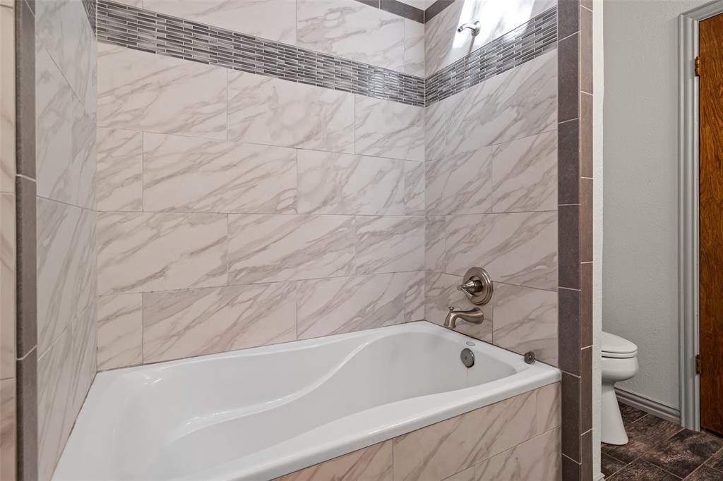 7508 Ravenswood Road Granbury, TX 76049 - Photo 29 of 40 a bathroom with a white bath tub and a shower