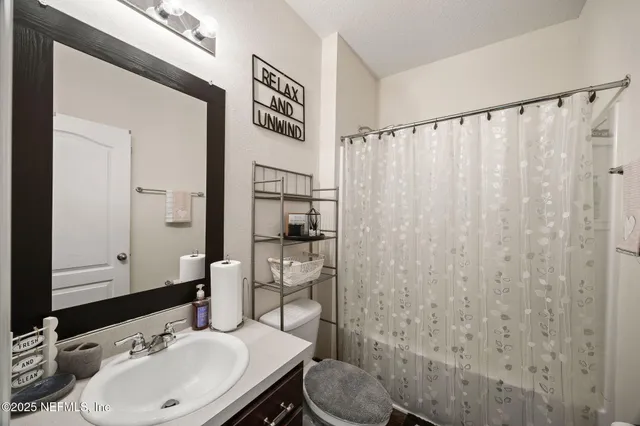 a bathroom with a sink a toilet and shower curtain