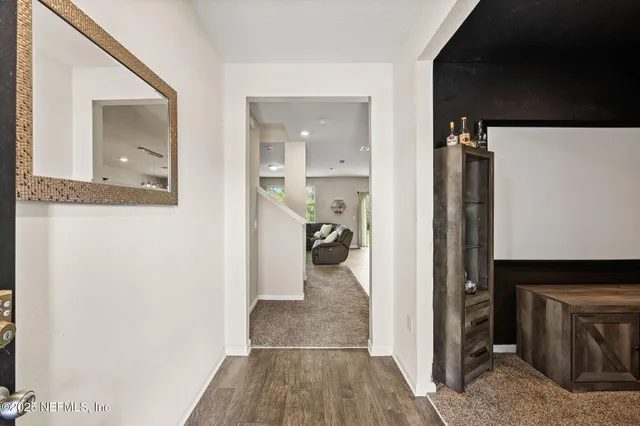 a view of a hallway with wooden floor and a bathroom