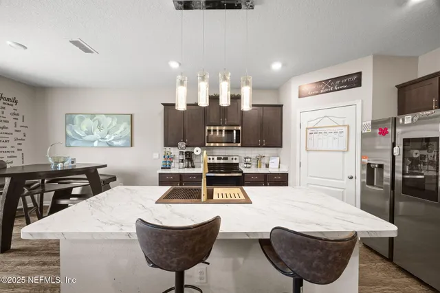 a kitchen with stainless steel appliances kitchen island granite countertop a dining table chairs and view of living room