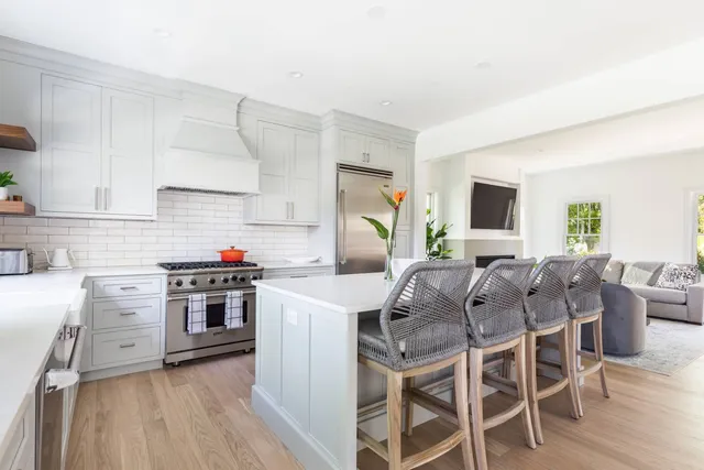 a kitchen with stainless steel appliances granite countertop a stove top oven a sink dishwasher and a refrigerator with wooden floor