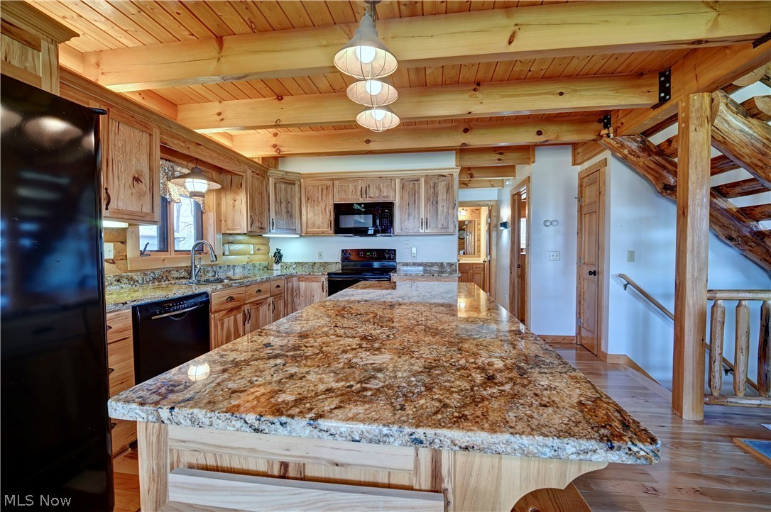 8045 McFadden Road Shreve, OH 44676 - Photo 24 of 45 Kitchen with a kitchen island, black appliances, light stone counters, light wood-type flooring, and a wooden ceiling with exposed beams