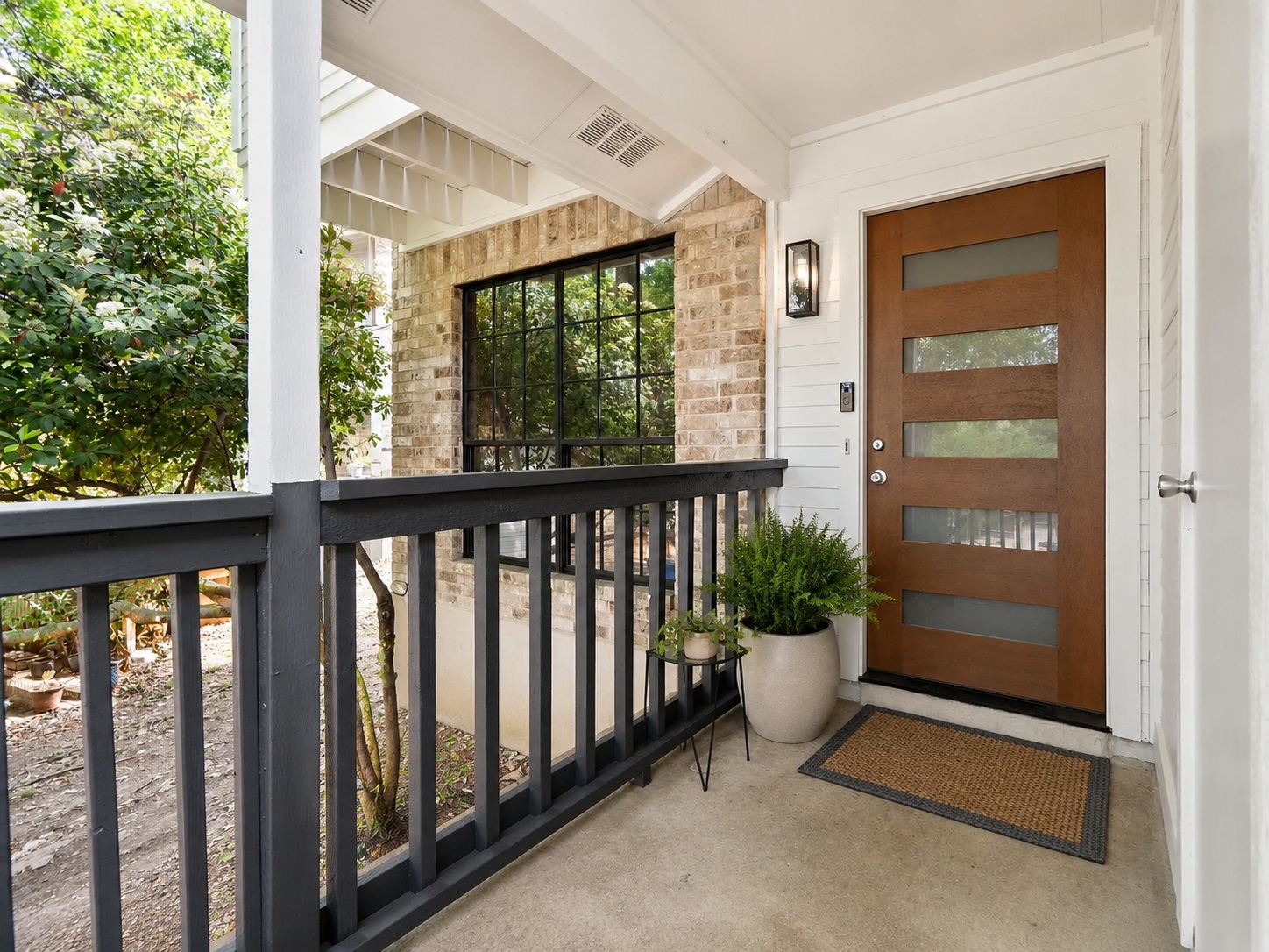 A welcoming front porch features a modern wood door with glass inserts, offering a warm approach.