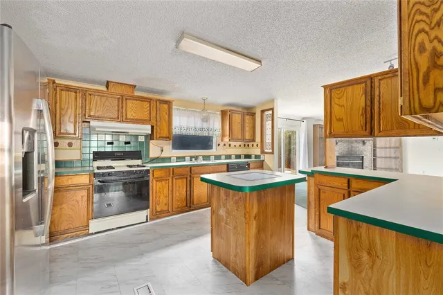 a kitchen with stainless steel appliances granite countertop a stove a sink and a refrigerator