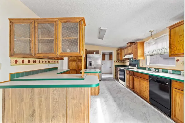 a kitchen with stainless steel appliances granite countertop a refrigerator a stove top oven and a sink with granite countertops