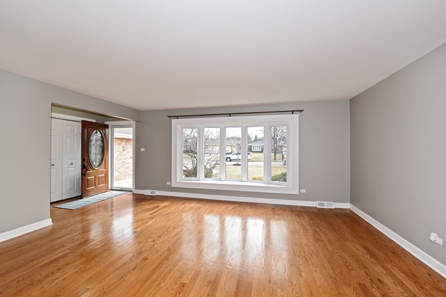 7706 Sawyer Road Darien, IL 60561 - Photo 4 of 10 an empty room with wooden floor and windows