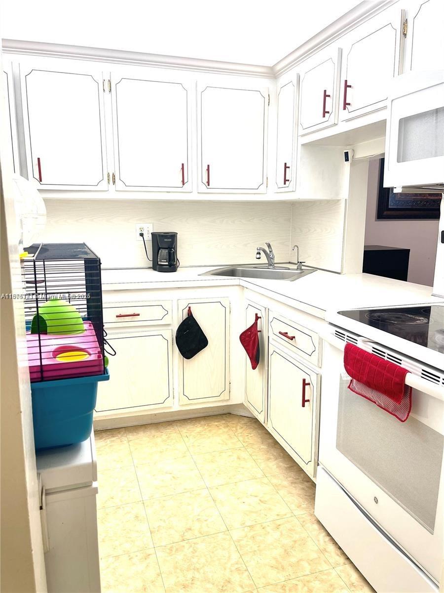 6071 Northwest 61st Avenue, Unit 311 Tamarac, FL 33319 - Photo 6 of 13 a kitchen with a sink a stove and white cabinets