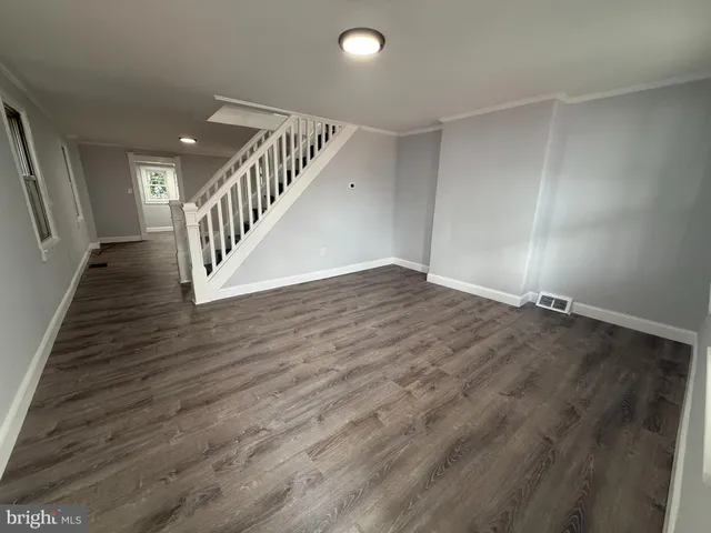 a view of an empty room with wooden floor and stairs