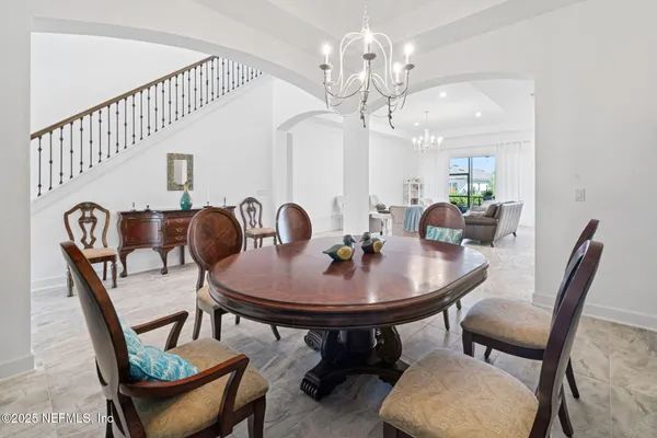 a living room with furniture a chandelier and a dining table