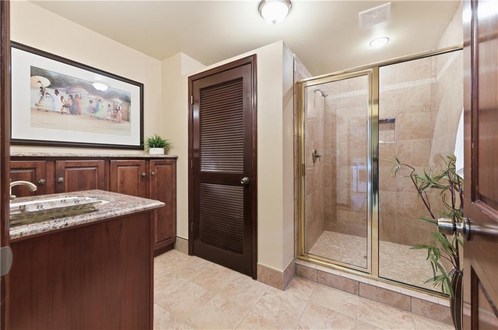 4220 Greentree Lane Southwest Atlanta, GA 30349 - Photo 18 of 42 a bathroom with a granite countertop sink a mirror and a shower
