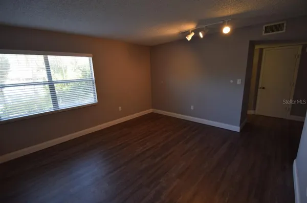 a view of an empty room with wooden floor and a window