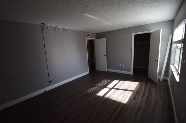 an empty room with wooden floor and windows