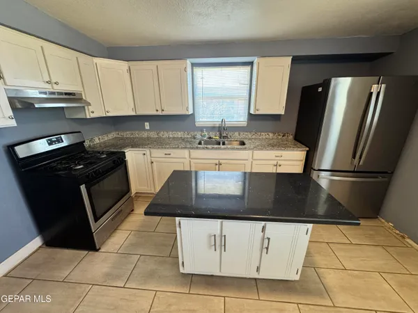 a kitchen with stainless steel appliances granite countertop a refrigerator and a stove