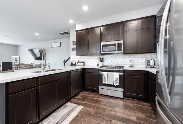 a kitchen with stainless steel appliances kitchen island granite countertop a refrigerator stove and sink