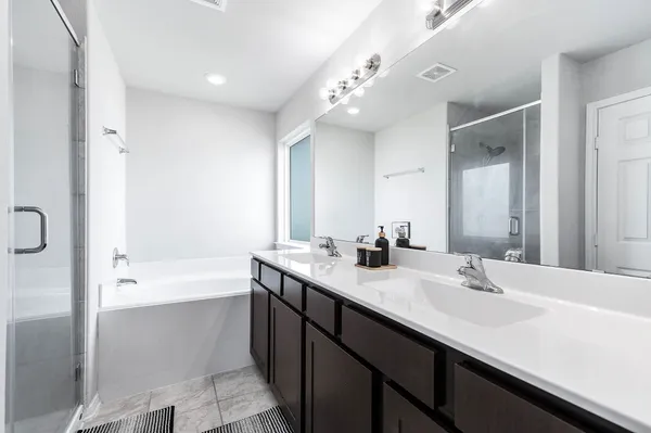 a bathroom with a sink double vanity granite tub shower and a mirror