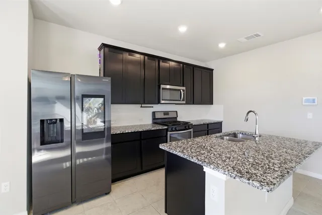 a kitchen with stainless steel appliances granite countertop a sink stove and refrigerator