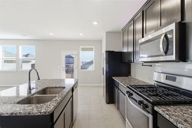 a kitchen with granite countertop a sink stainless steel appliances and cabinets