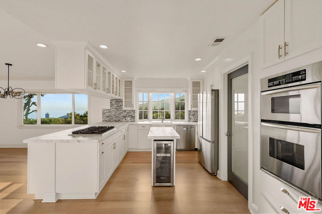 204 Tranquillo Road Pacific Palisades, CA 90272 - Photo 19 of 34 a kitchen with stainless steel appliances granite countertop a refrigerator oven a sink dishwasher and white cabinets with wooden floor