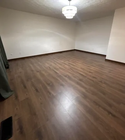 an empty room with wooden floor and mirror