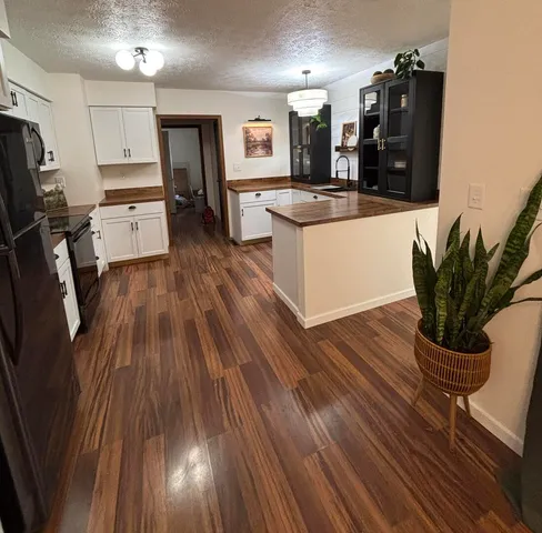 a kitchen with stainless steel appliances granite countertop a refrigerator a stove and a wooden floors