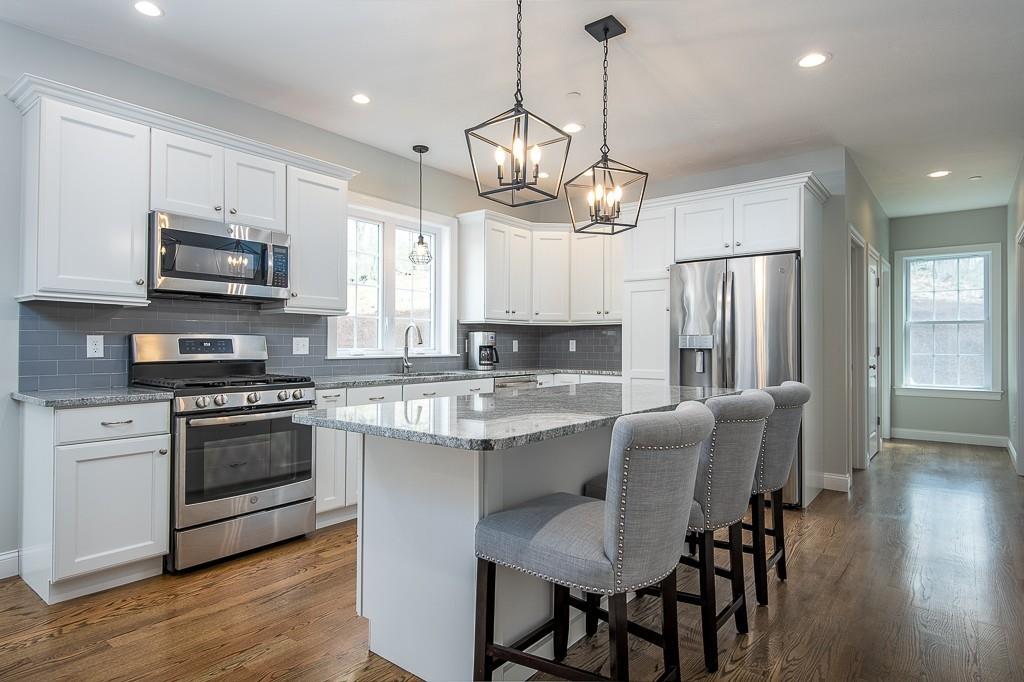 222 Sugar Road Bolton, MA 01740 - Photo 5 of 36 a kitchen with stainless steel appliances granite countertop a stove a sink dishwasher a refrigerator and a dining table with wooden floor