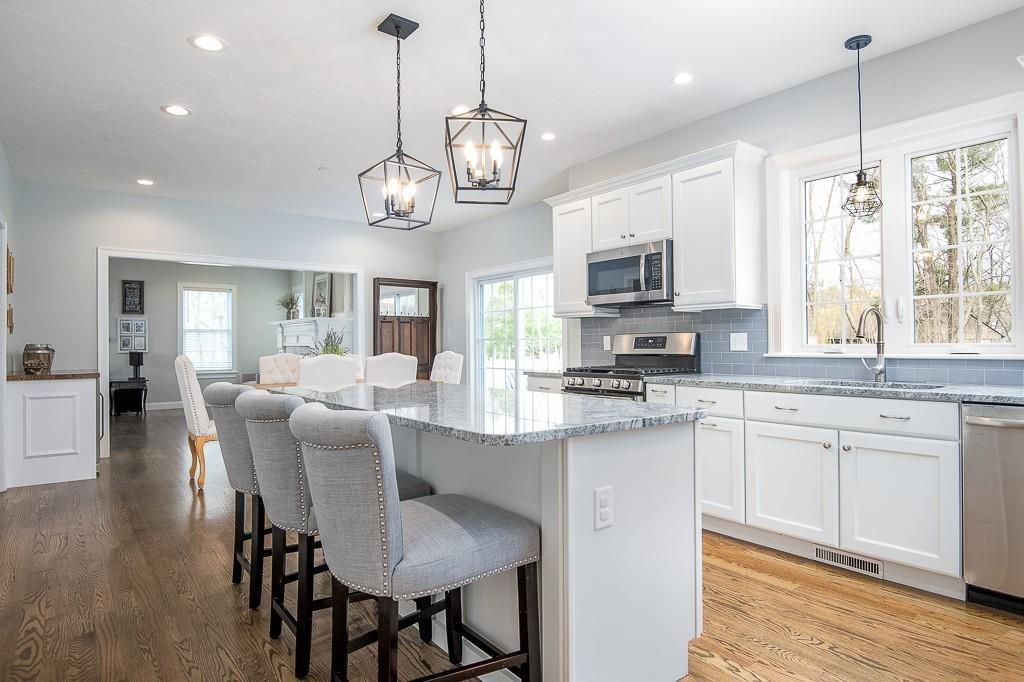222 Sugar Road Bolton, MA 01740 - Photo 6 of 36 a kitchen with stainless steel appliances granite countertop granite countertop a stove top oven a refrigerator a sink dishwasher a dining table and chairs with wooden floor