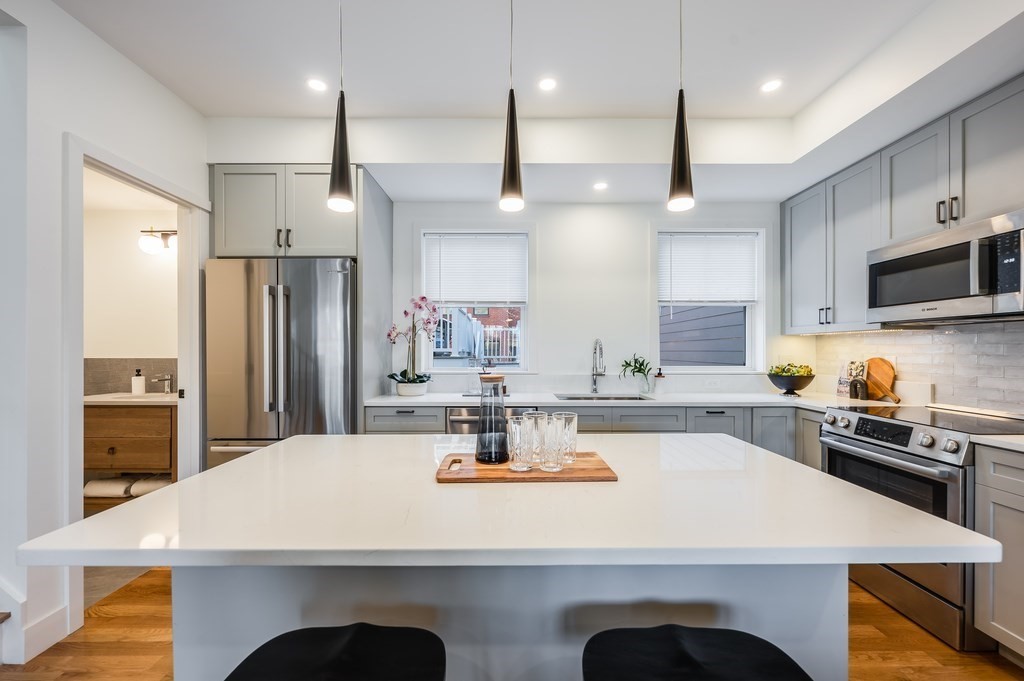 96 Otis Street, Unit 2 Cambridge, MA 02141 - Photo 14 of 42 a kitchen with a refrigerator a sink a stove and chairs with wooden floor