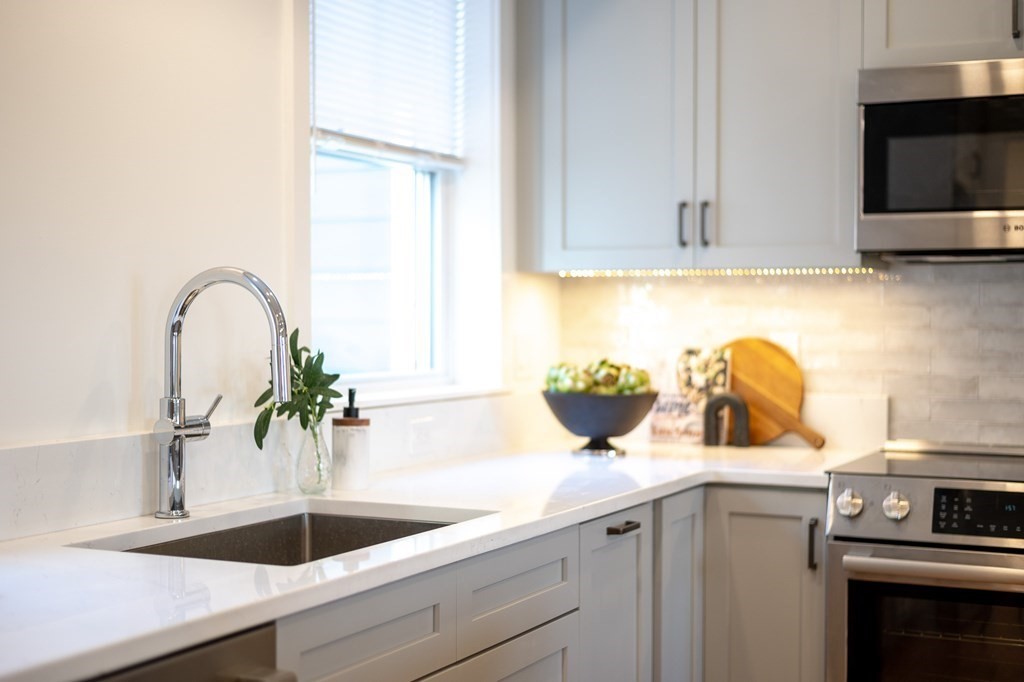 96 Otis Street, Unit 2 Cambridge, MA 02141 - Photo 10 of 42 a kitchen with a sink and a stove with wooden floor