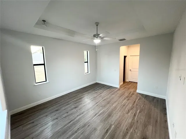 an empty room with wooden floor chandelier and windows