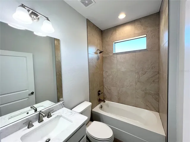 a bathroom with a bathtub shower sink vanity and toilet