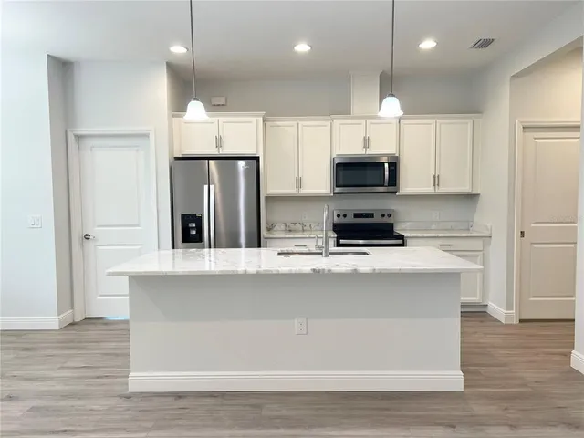 a kitchen with kitchen island white cabinets and refrigerator