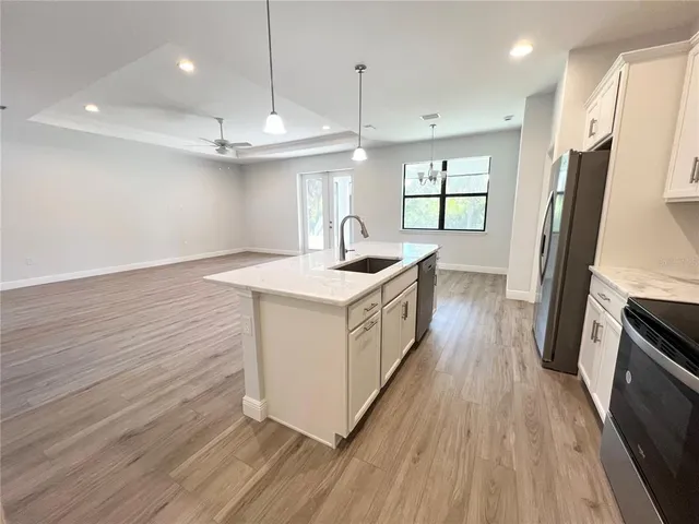 a kitchen with stainless steel appliances granite countertop a sink a stove a refrigerator and wooden floor