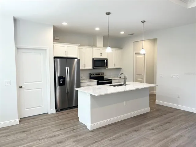 a kitchen with kitchen island a refrigerator and a stove top oven