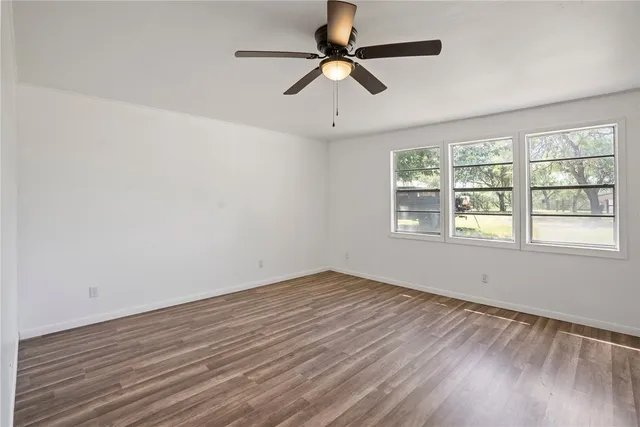 a view of room with hardwood floor and a ceiling fan