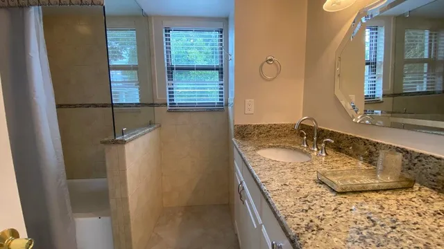 a bathroom with a granite countertop sink and a mirror