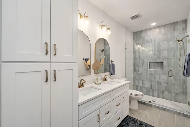 a bathroom with a double vanity sink toilet and shower