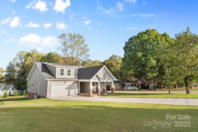 a front view of a house with a big yard and large trees