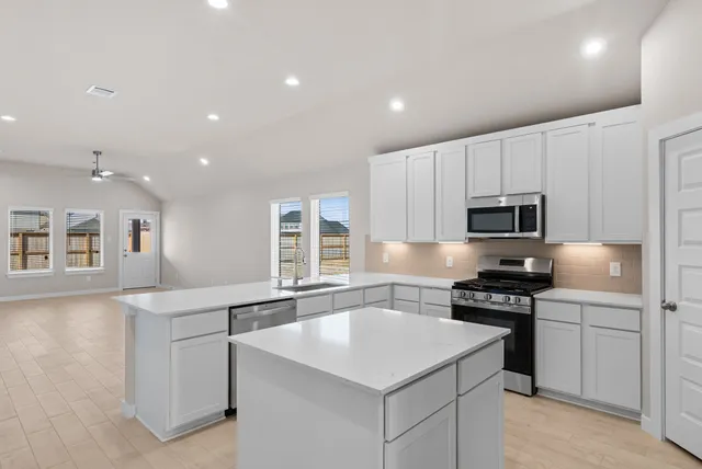 a kitchen that has a sink a stove and chairs