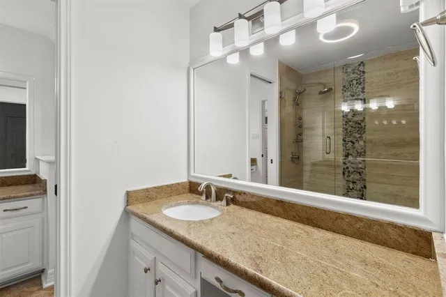 a bathroom with a granite countertop sink and a mirror