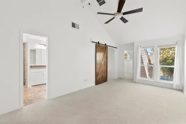 an empty room with chandelier fan and windows