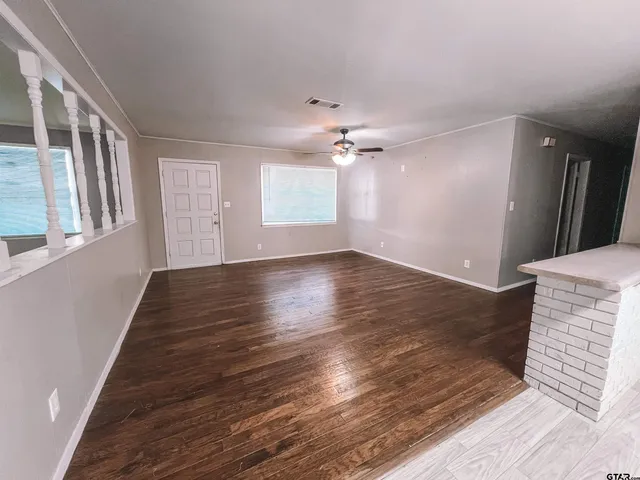 a view of an empty room with wooden floor and a window