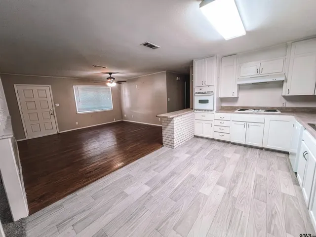 a large kitchen with cabinets wooden floor and stainless steel appliances