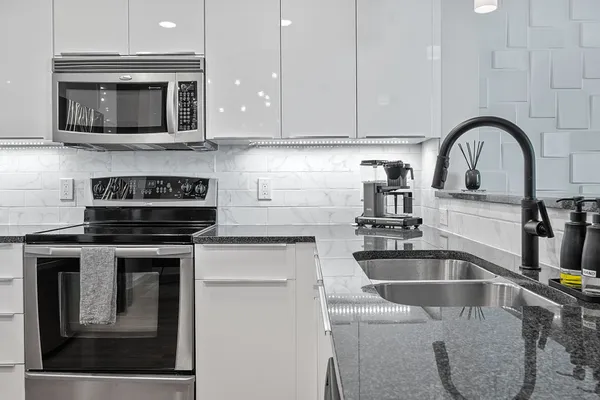 a kitchen with granite countertop a stove a microwave a sink and cabinets